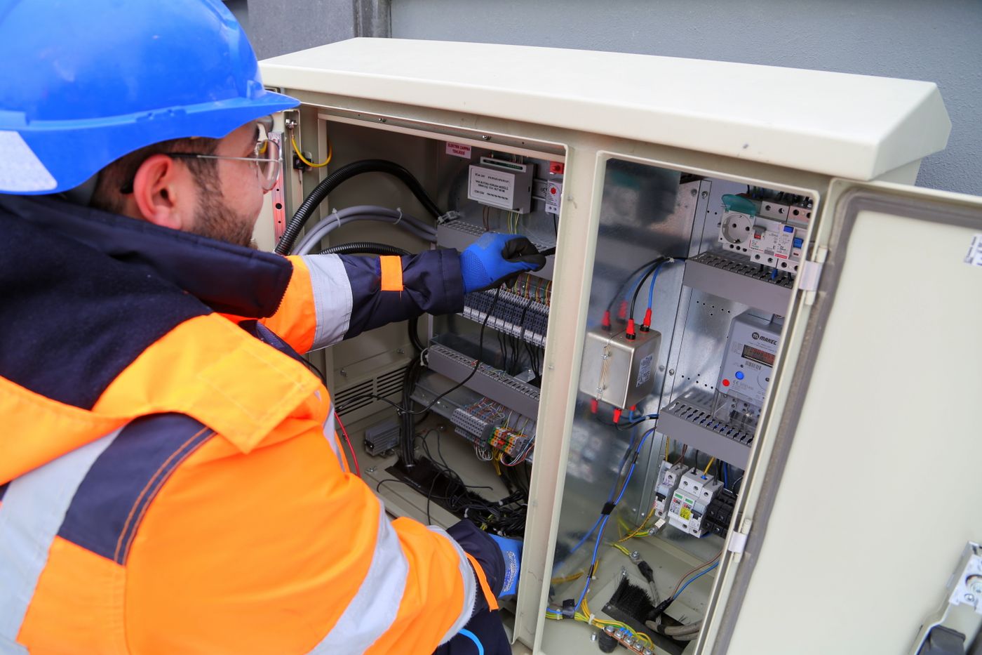 Technician in safety gear servicing an electrical panel